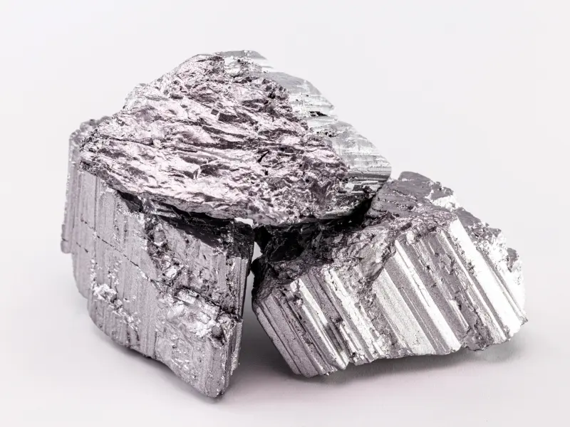 Silvery pieces of erbium metal on a light background